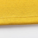 Close-up of a yellow fabric featuring edge stitching, reminiscent of Classic Sportswear's Limited Edition Hurricanes Super Rugby 25/26 Retro Jersey, against a white background.