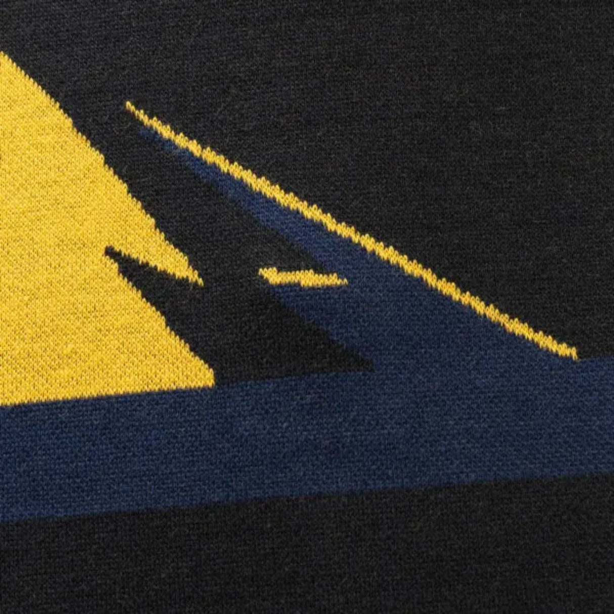 Close-up of a knitted fabric featuring abstract geometric patterns in yellow, black, and dark blue, reminiscent of the Limited Edition Hurricanes Super Rugby 25/26 Retro Jersey by Classic Sportswear.