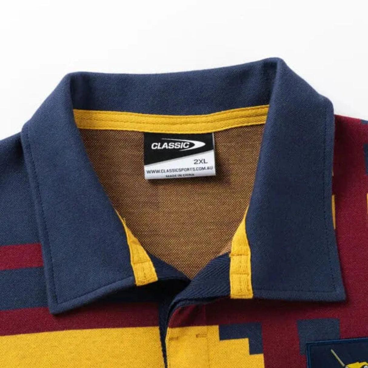 A close-up of a collared shirt in blue, maroon, and yellow geometric patterns evokes the Retro Jersey style. Inside the collar is a "CLASSIC" tag indicating size "2XL." It's the Limited Edition Highlanders Super Rugby 25/26 Retro Jersey by Classic Sportswear.