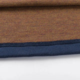 A close-up showcases the textured brown pattern and contrasting dark blue edge of the Limited Edition Highlanders Super Rugby 25/26 Retro Jersey by Classic Sportswear, reminiscent of classic sportswear, set against a white surface.