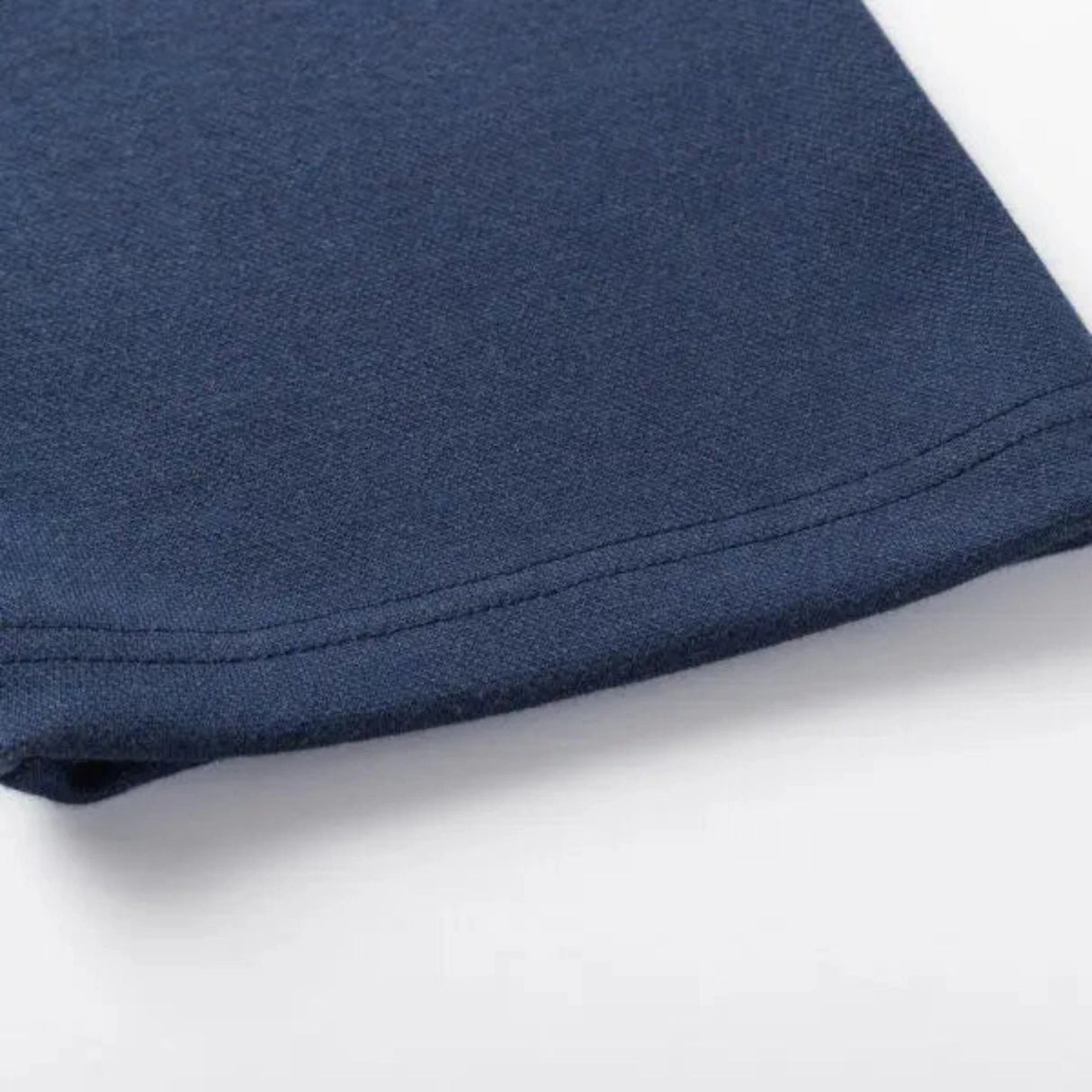 Close-up of the hem of a dark blue fabric, reminiscent of the Limited Edition Highlanders Super Rugby 25/26 Retro Jersey by Classic Sportswear, displayed on a light surface.