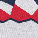 Close-up of a knitted fabric with a geometric pattern showing red and black zigzag shapes on white, reminiscent of the Limited Edition Blues Super Rugby 25/26 Retro Jersey by Classic Sportswear.