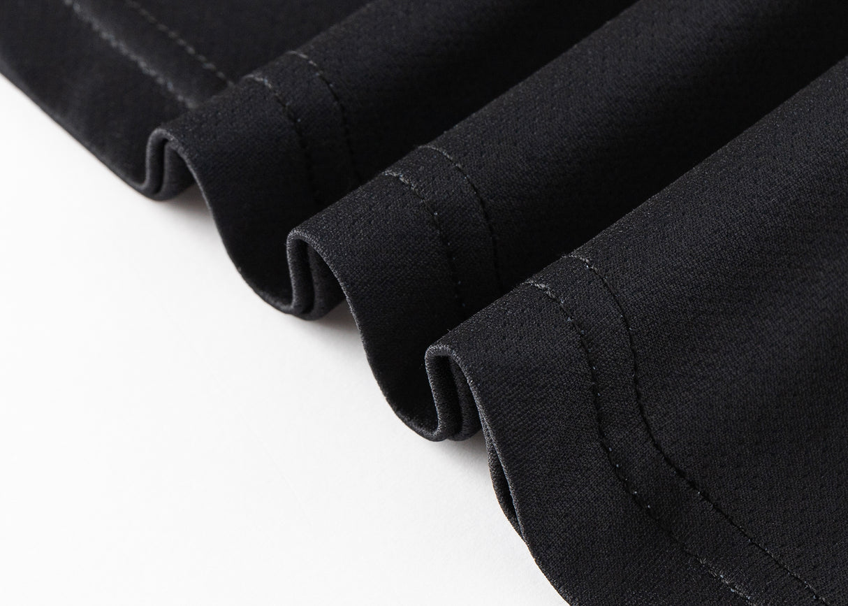Close-up of the hem of a moisture-wicking black fabric from the Gallagher Chiefs Super Rugby 25/26 Team Polo by Classic Sportswear, showing four neatly folded edges on a white background.
