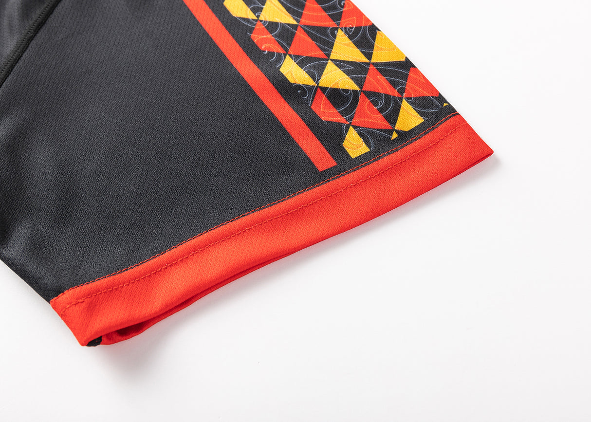 Close-up of the Gallagher Chiefs Super Rugby 25/26 Team Polo by Classic Sportswear features a black, moisture-wicking fabric with a red, yellow, and black geometric pattern on one side, complemented by red trim at the hem—perfect for Chiefs fans.