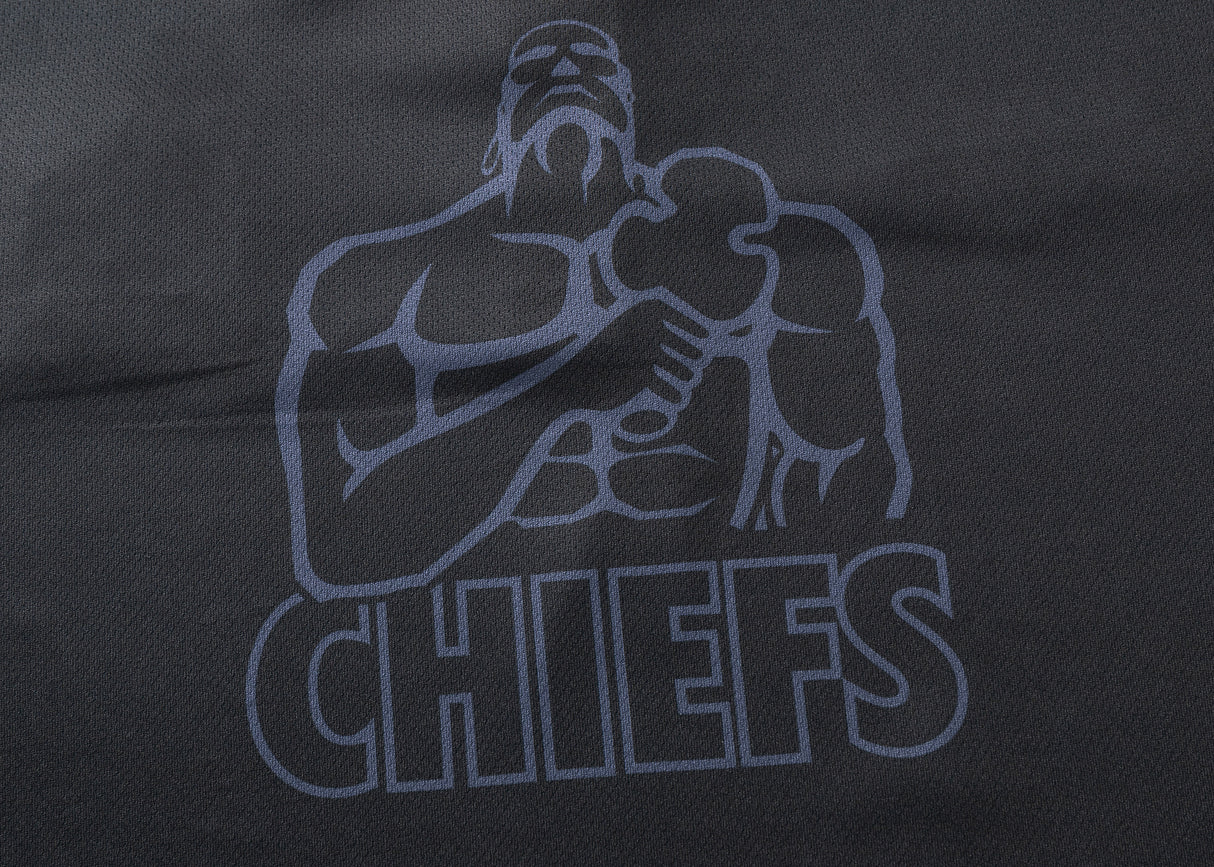 A muscular figure with a clenched fist and Chiefs logo is printed in dark color on a textured black background, echoing the bold designs of the Gallagher Chiefs Super Rugby 25/26 Team Polo by Classic Sportswear.