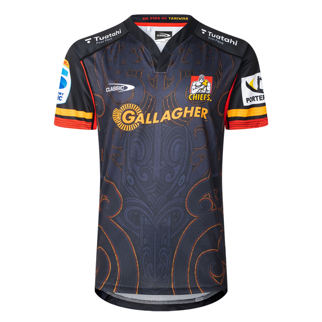 The Classic Sportswear Gallagher Chiefs Super Rugby Replica Home Jersey 25/26 features a dark intricate pattern, with the "Gallagher" text, Chiefs logo, and sponsor logos on the sleeves. Ideal for any Super Rugby fan eager to support the team proudly.