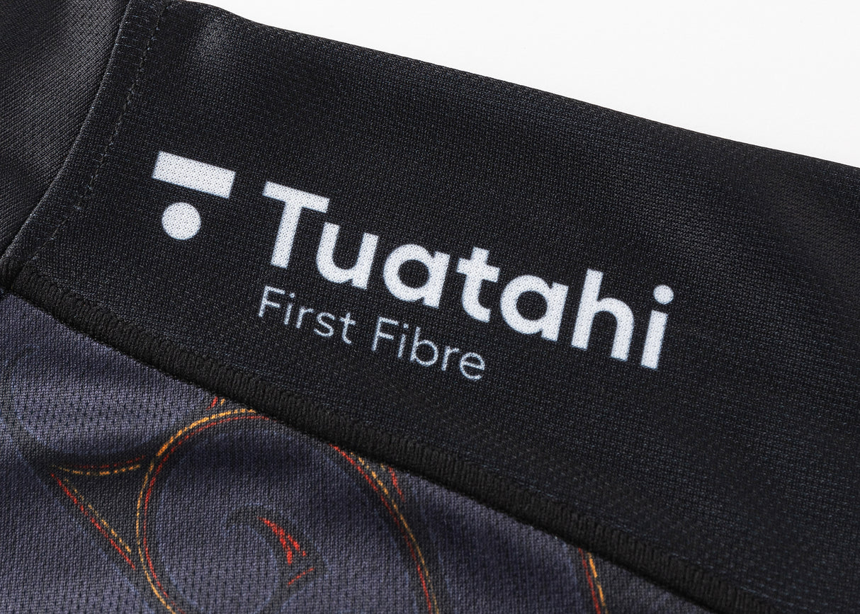 Close-up of a black fabric featuring the white "Tuatahi First Fibre" logo, similar to the iconic pattern of the Classic Sportswear Gallagher Chiefs Super Rugby Replica Home Jersey 25/26.
