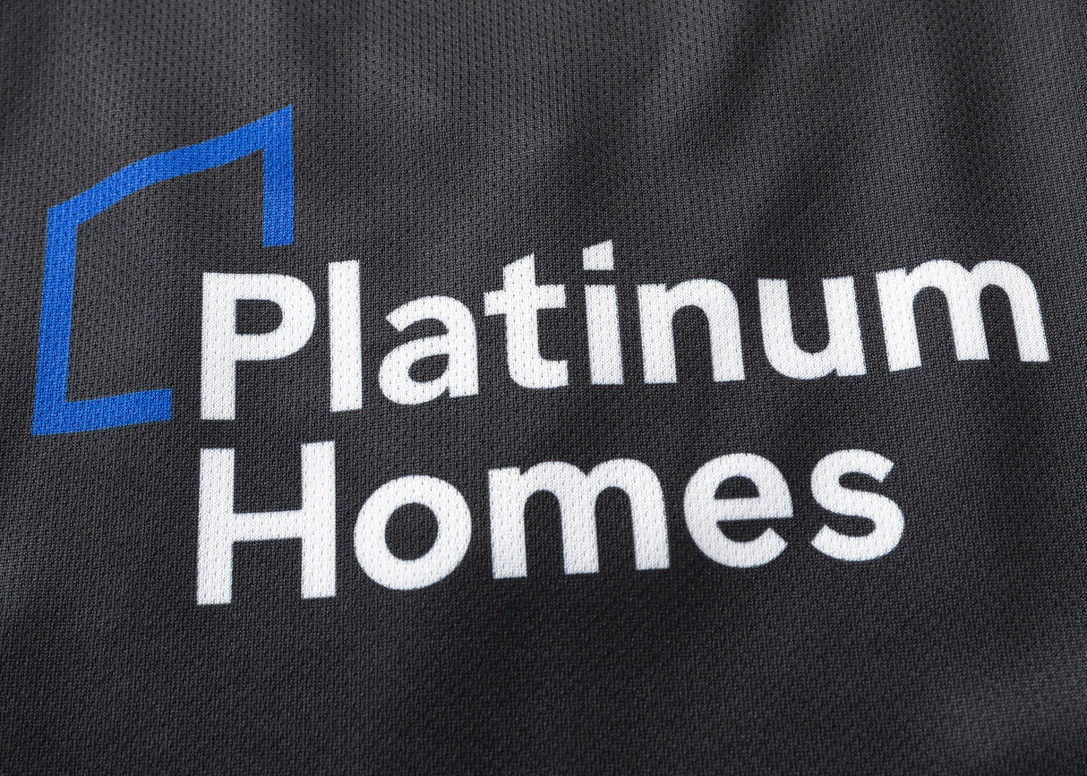 The image features a dark fabric similar to the Gallagher Chiefs Super Rugby Replica Home Jersey 25/26 by Classic Sportswear, with "Platinum Homes" in white letters and a blue geometric shape.