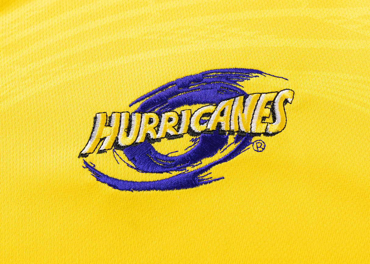 Yellow fabric jersey featuring a purple and yellow embroidered "HURRICANES" logo with a swirling design, reminiscent of the Hurricanes Super Rugby 25/26 Replica Home Jersey by Classic Sportswear.