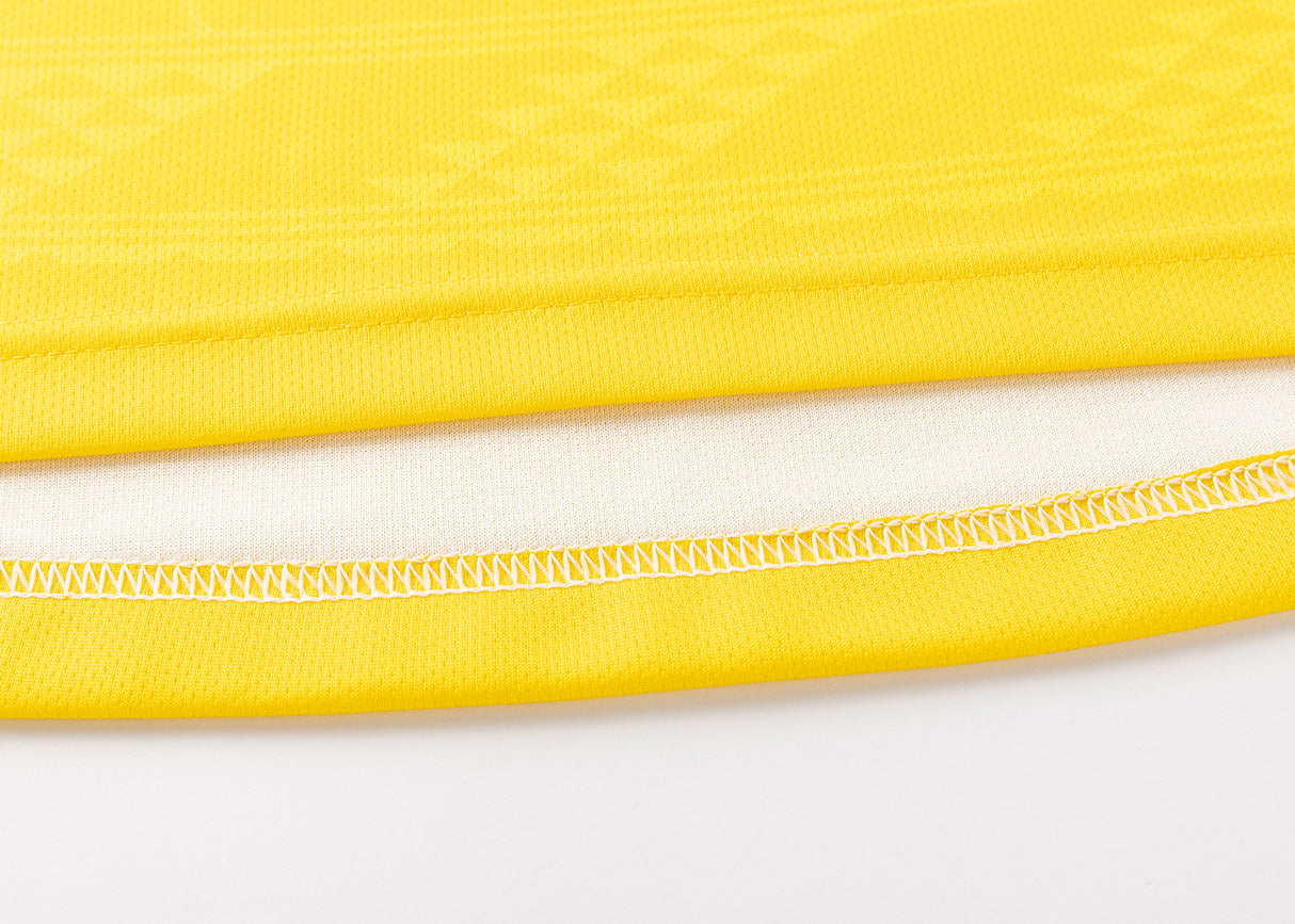 Close-up of the edge of a yellow fabric, reminiscent of the Hurricanes Super Rugby 25/26 Replica Home Jersey by Classic Sportswear, with visible stitching highlighting a white inner layer.