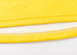 Close-up of the edge of a yellow fabric, reminiscent of the Hurricanes Super Rugby 25/26 Replica Home Jersey by Classic Sportswear, with visible stitching highlighting a white inner layer.