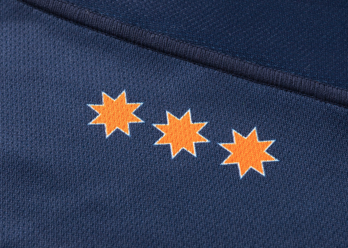 Close-up of a dark blue fabric with three orange eight-pointed stars in a row, echoing the design of the Highlanders Super Rugby 25/26 Replica Home Jersey by Classic Sportswear.