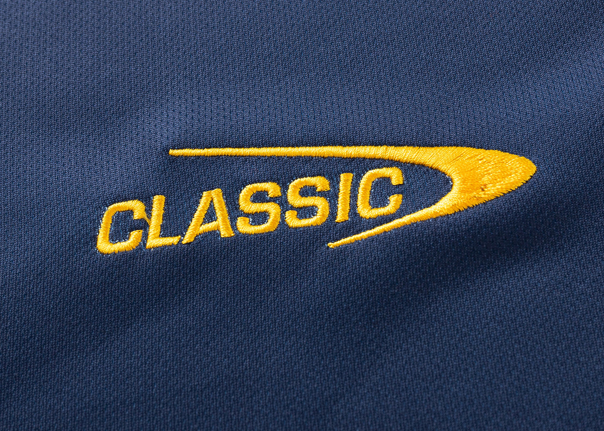 The Highlanders Super Rugby 25/26 Replica Home Jersey by Classic Sportswear features blue fabric with "CLASSIC" in yellow embroidered text, a curved design, and moisture-wicking material to keep you comfortable and dry.