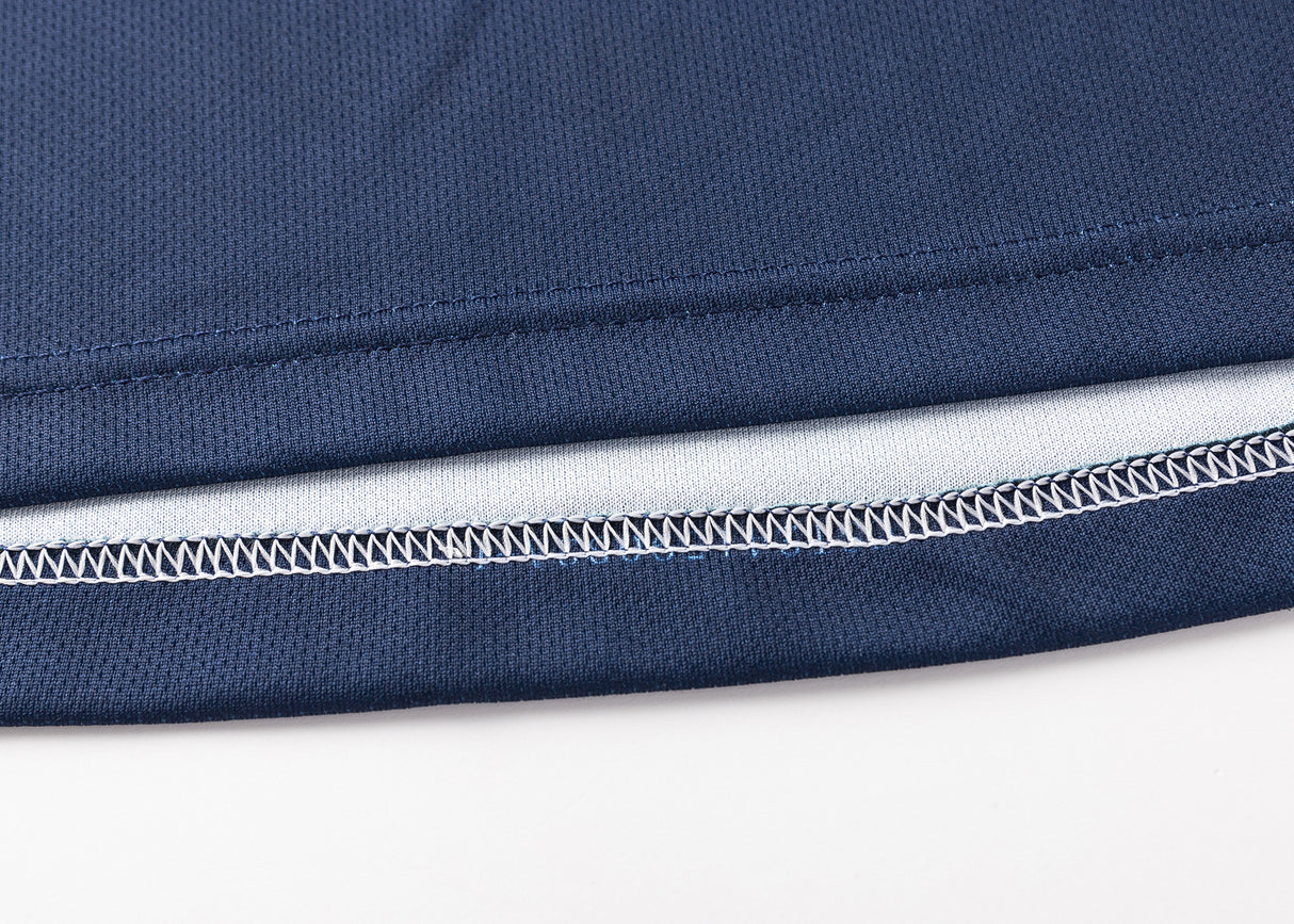 Close-up of the hem of a blue fabric resembling the Highlanders Super Rugby 25/26 Replica Home Jersey by Classic Sportswear, highlighting detailed stitching and a white inner lining with moisture-wicking technology.