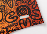 Close-up of an orange and black fabric with abstract patterns, resembling the NRL Indigenous All Stars 25/26 Pro Training Singlet by Classic Sportswear, showcasing a small tag reading "STAY COOL™.