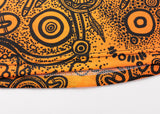 Close-up of an orange fabric with black abstract circular and dotted patterns, resembling the dynamic designs on the NRL Indigenous All Stars 25/26 Pro Training Singlet by Classic Sportswear.