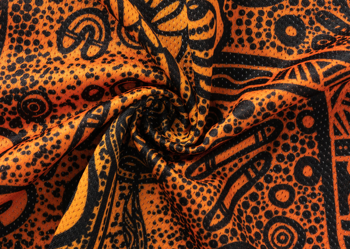 Close-up of the NRL Indigenous All Stars 25/26 Pro Training Singlet by Classic Sportswear, displaying orange and black patterned fabric with intricate abstract designs. Swirls and dots add texture, highlighting Classic Sportswear's craftsmanship.
