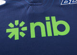 Close-up of a dark blue polo with the green "nib" logo. The Blues Super Rugby 25/26 Team Polo by Classic Sportswear exudes timeless sportswear charm, blending heritage and performance in every stitch.