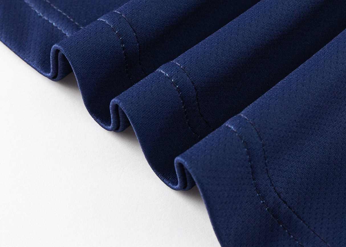 A close-up of the Blues Super Rugby 25/26 Team Polo by Classic Sportswear showcases neat, wavy pleats and visible stitching on blue fabric, reflecting a dynamic sports spirit against a pristine white background.