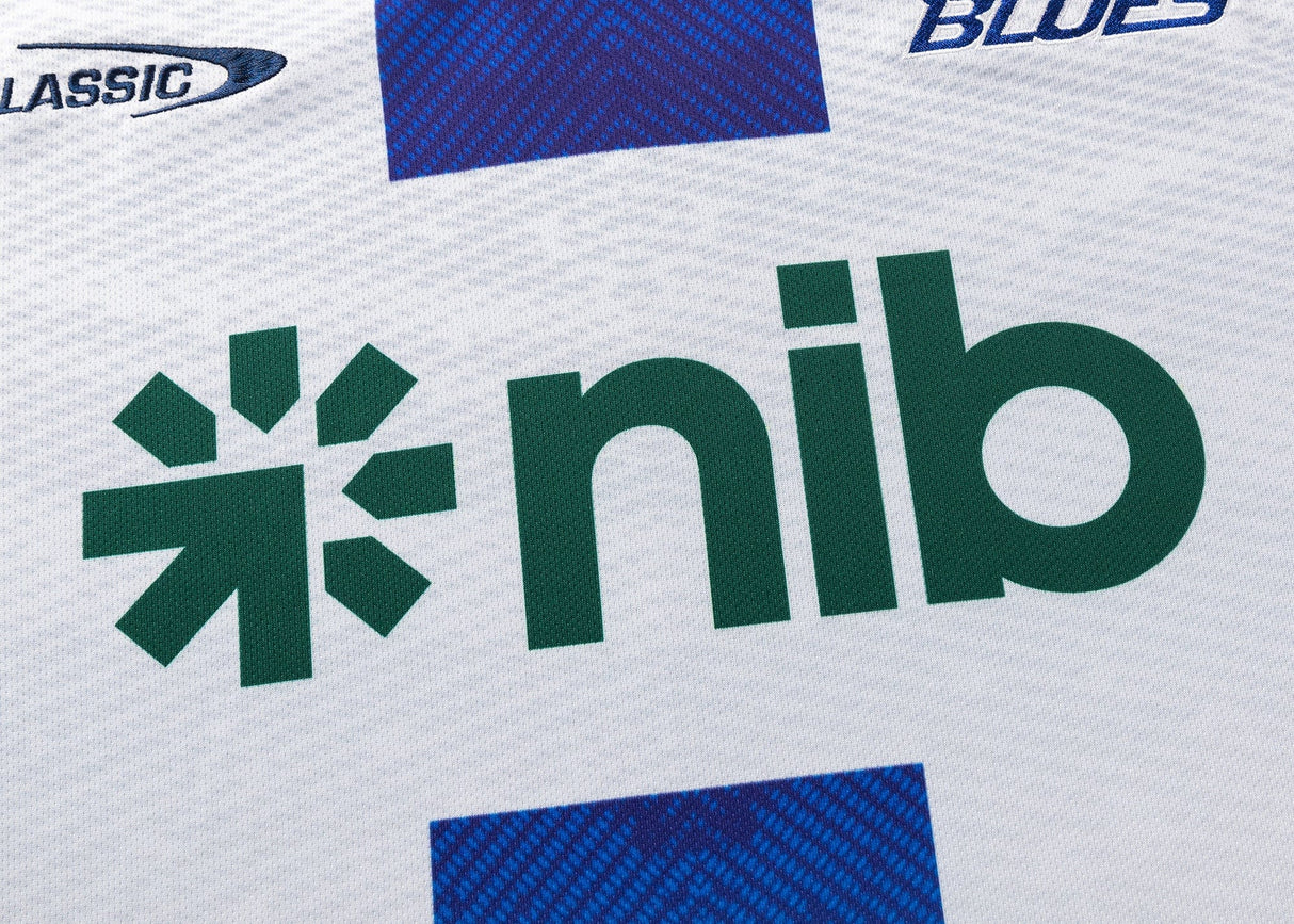 Close-up of a white Blues Super Rugby 25/26 Replica Away Jersey by Classic Sportswear with "nib" in green lettering and logos for Classic Sportswear and Blues Super Rugby.