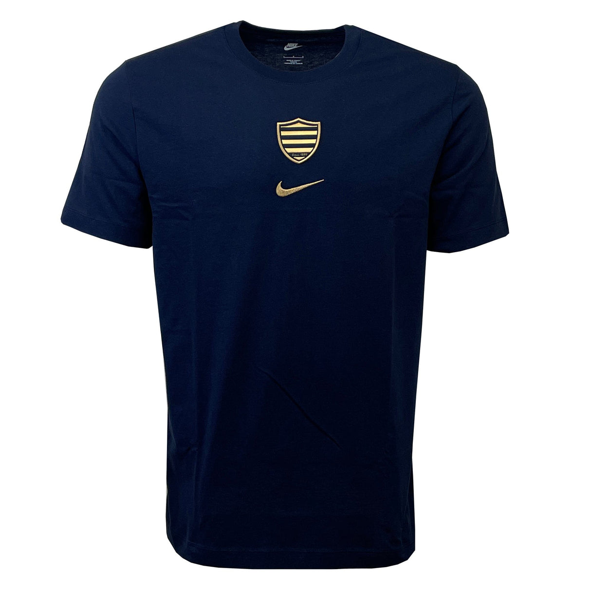 The Racing 92 Evergreen Tee 1 by Nike is a navy blue tee designed from premium cotton jersey, adorned with a small golden shield emblem and a gold Nike swoosh logo on the chest.