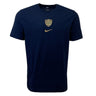 The Racing 92 Evergreen Tee 1 by Nike is a navy blue tee designed from premium cotton jersey, adorned with a small golden shield emblem and a gold Nike swoosh logo on the chest.