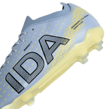 Close-up of the IDA Sports IDA Helia Club FG women's soccer cleat in light blue, showcasing yellow geometric patterns and translucent yellow sole studs, with "IDA" printed on the side.