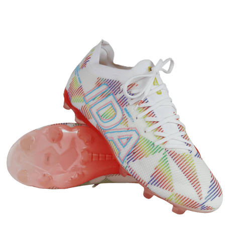 A pair of IDA Sports Helia Elite Limited Edition Pride FG women's soccer cleats in white, with multicolored geometric patterns, "IDA" branding on the side, and pink-tinted translucent firm ground soles.