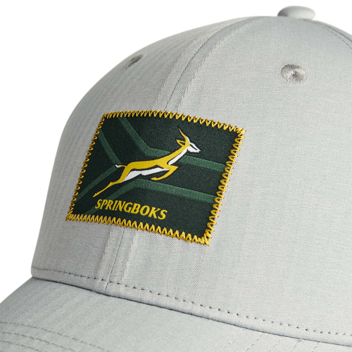 Close-up of the Nike Springboks 26/27 RGR Legacy 91 Club Cap in light gray, showcasing a rectangular green patch with yellow trim, an antelope design, and “SPRINGBOKS” embroidered at the front—a must-have accessory for any rugby fan.