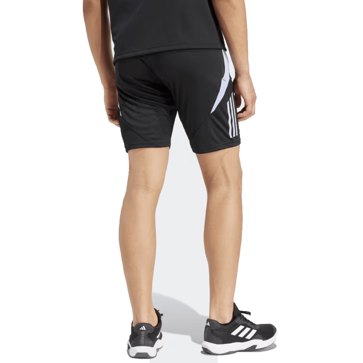 A person wearing the All Blacks 24/25 Performance Gym Shorts by Adidas, a black shirt, and black sneakers with white details stands on a white background.