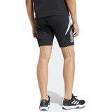 A person wearing the All Blacks 24/25 Performance Gym Shorts by Adidas, a black shirt, and black sneakers with white details stands on a white background.