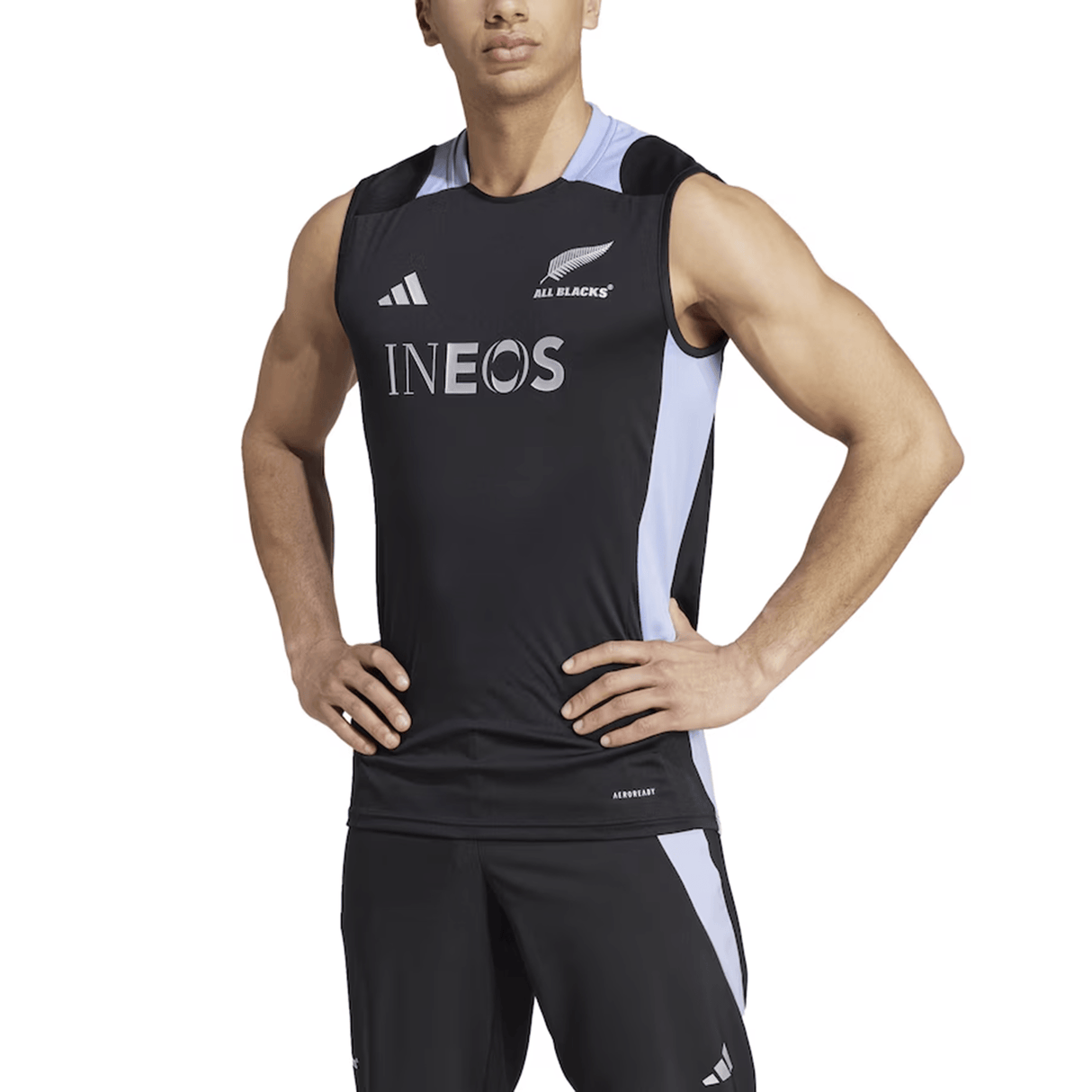 A person is wearing the All Blacks 24/25 Performance Singlet by adidas, a sleeveless black jersey designed with the "All Blacks" and "INEOS" logos, crafted using Adidas AEROREADY technology for optimal comfort and performance.