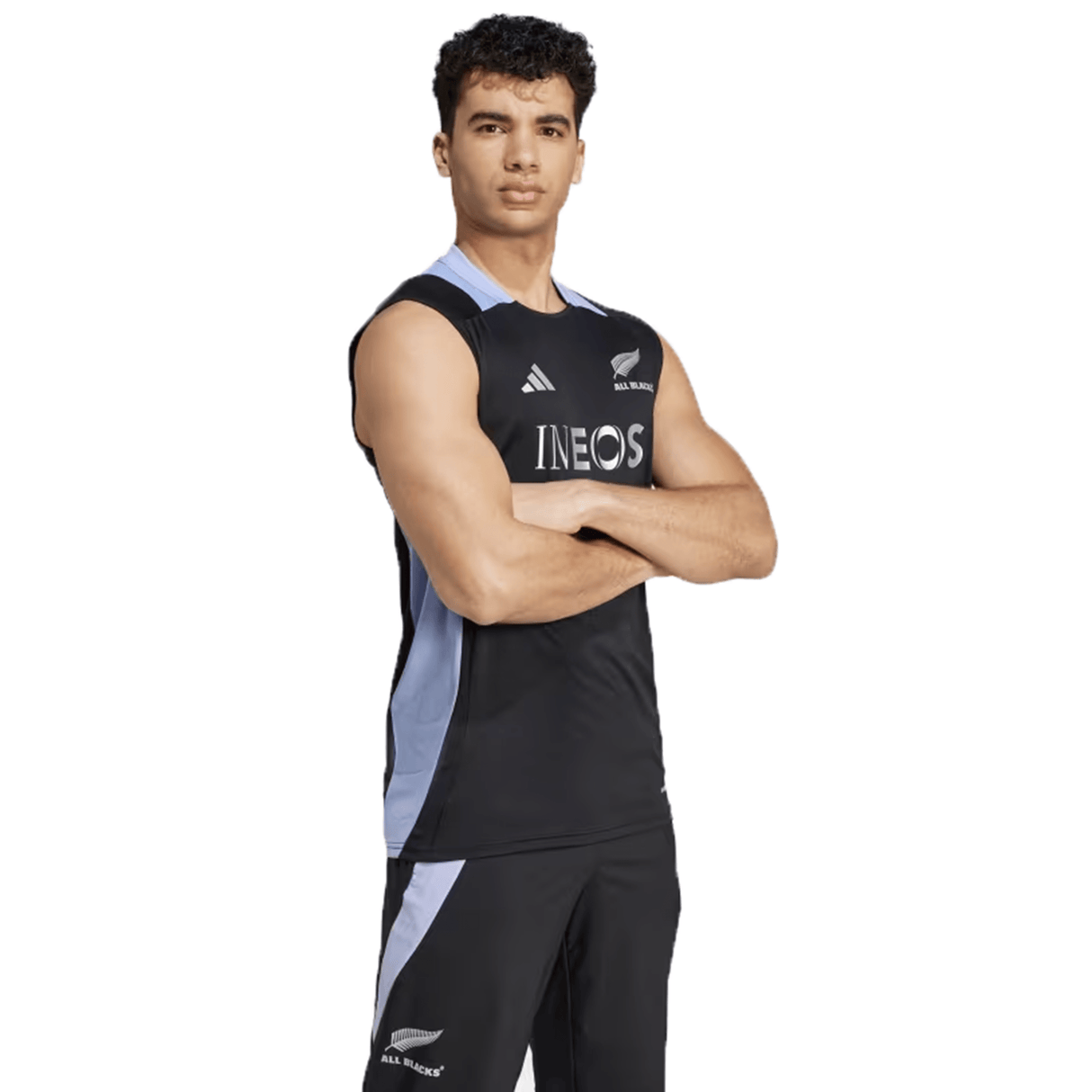 Wearing the All Blacks 24/25 Performance Singlet by adidas, a person stands confidently with arms crossed, embodying the spirit of the renowned team.