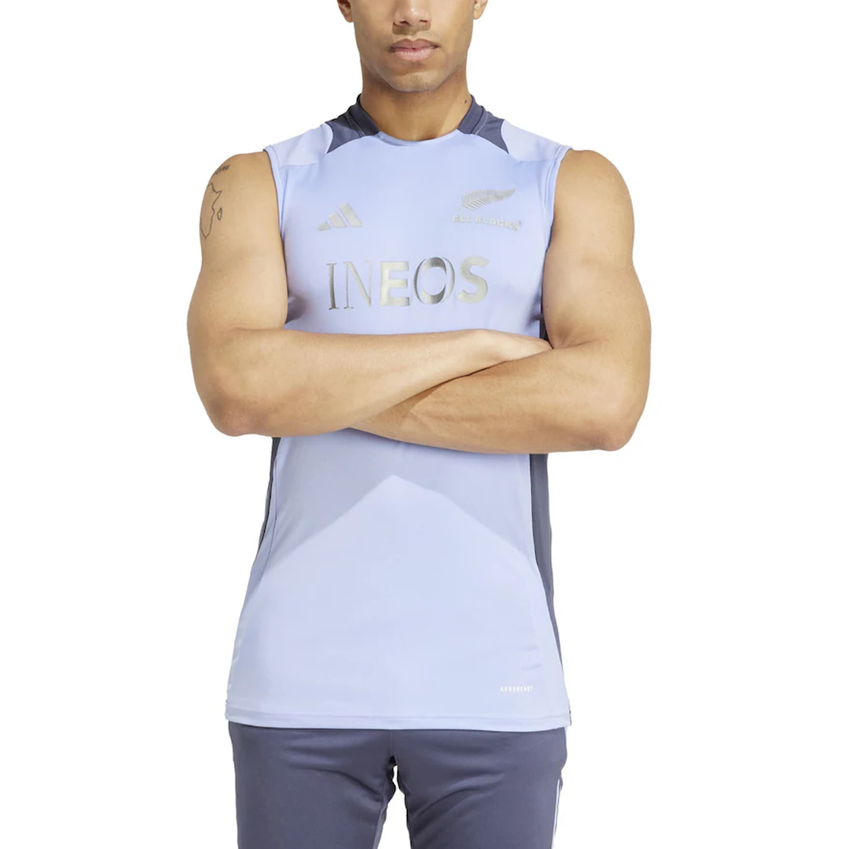 A person confidently stands with crossed arms, wearing the adidas All Blacks 24/25 Performance Training Singlet, embodying the spirit of performance training.