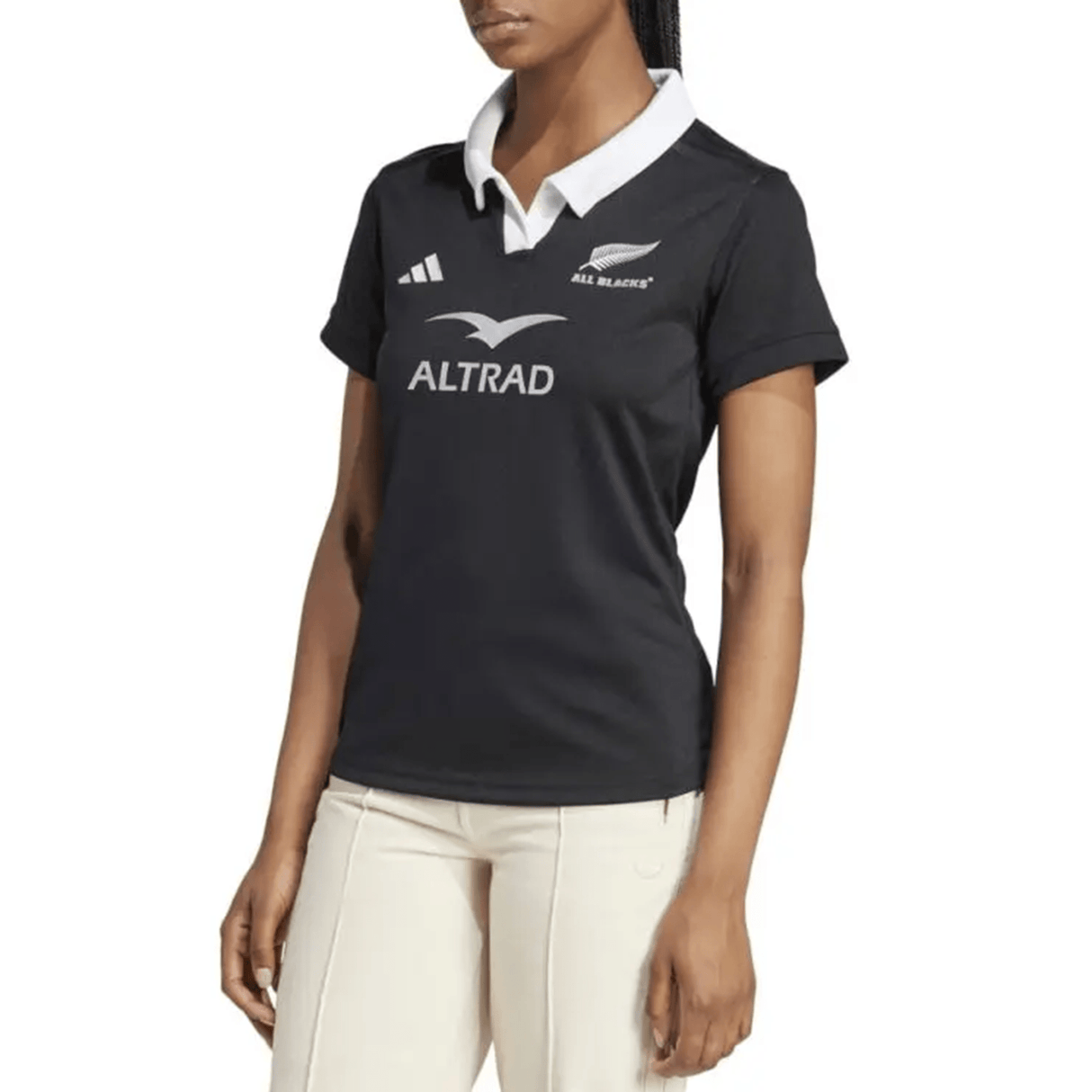 A person is seen in light-colored pants and the Women's All Blacks 24/25 Home Supporters Jersey by adidas, adorned with "ALL BLACKS" and "ALTRAD" logos. This jersey features AEROREADY technology for enhanced comfort.