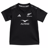 The Infant All Blacks 24/25 Home Kit by adidas features a black rugby jersey with logos "25 YEARS," "ALL BLACKS," and "ALTRAD." It has three white shoulder stripes, the adidas logo on the chest, and AEROREADY technology for enhanced comfort.