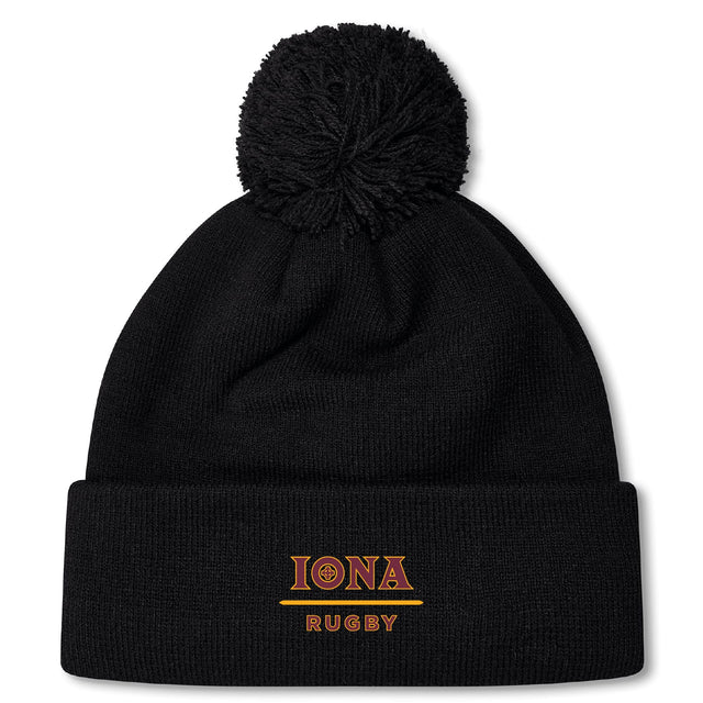 The Iona College Pom Pom Beanie by EMB Canterbury is a black fleece-lined hat featuring a pom-pom and "IONA RUGBY" embroidered in gold and red on the front cuff.
