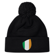 The EMB Canterbury Ireland Shield Pom Pom Beanie features a stylish shield emblem with green, white, and orange vertical stripes, reminiscent of the Ireland flag.