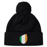 The EMB Canterbury Ireland Shield Pom Pom Beanie features a stylish shield emblem with green, white, and orange vertical stripes, reminiscent of the Ireland flag.