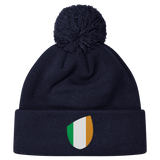 The Ireland Shield Pom-Pom Beanie by EMB Canterbury features a vibrant green, white, and orange Ireland shield emblem on a navy blue background.