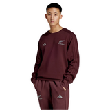 A person in an All Blacks 24/25 Fan Crewneck Sweatshirt by adidas and logo-adorned pants stands confidently against a plain background.