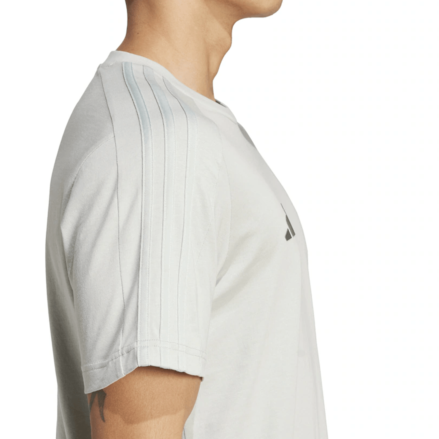 A person in an All Blacks 24/25 Fan Tee by adidas, featuring light gray fabric and 3-Stripes on the shoulders, facing sideways.