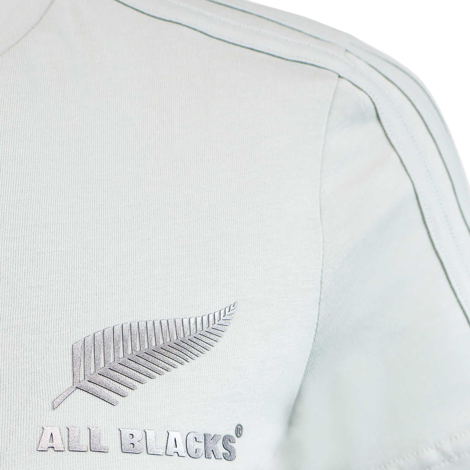 The Women’s All Blacks 24/25 Fan Tee by adidas is a light-colored tee featuring “ALL BLACKS” text and a silver fern logo—ideal for fans of New Zealand’s legendary rugby team.
