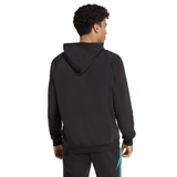 A man stands facing away, wearing the adidas All Blacks 25/26 Training Hoodie and matching black pants with teal stripes—ideal rugby fan apparel.