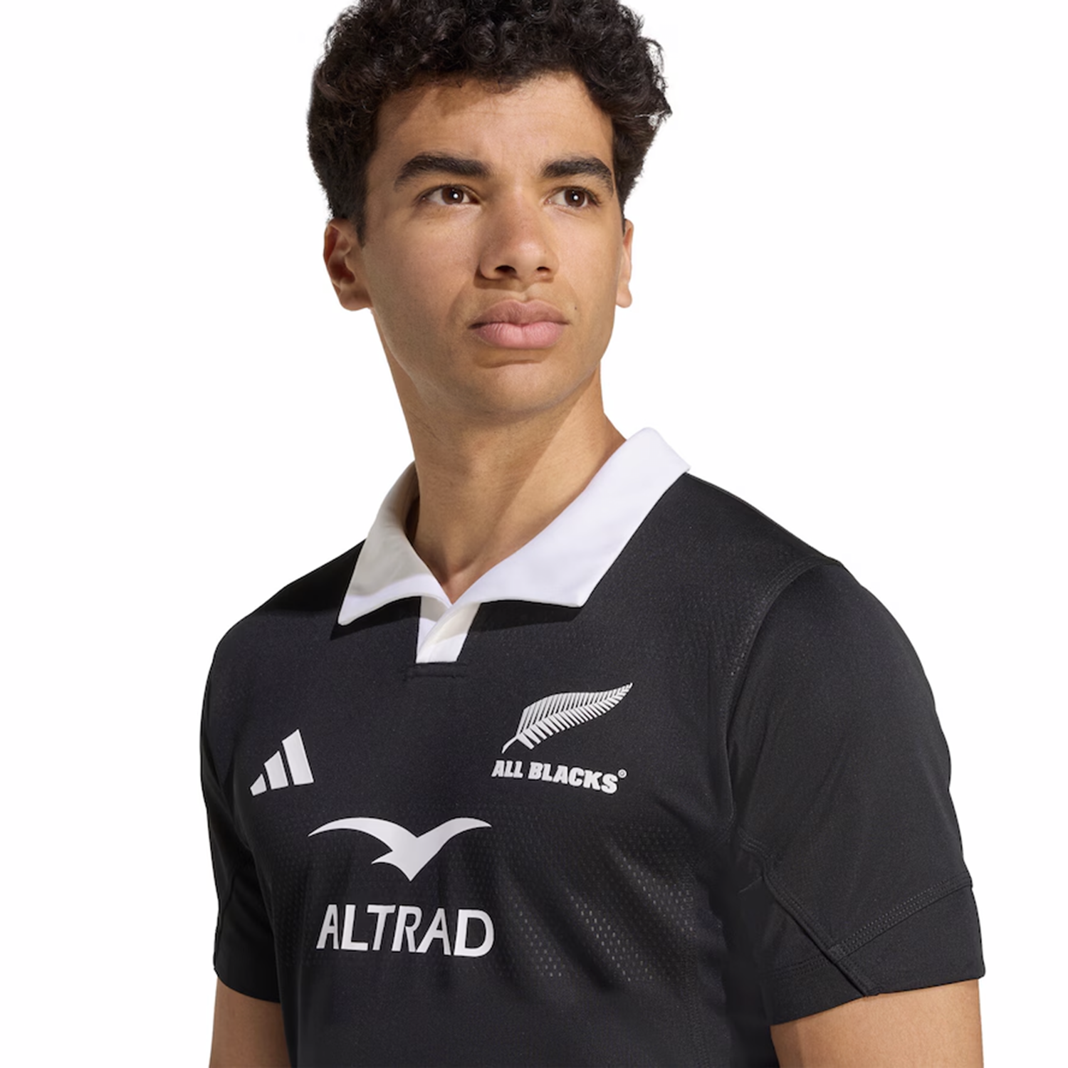 A person models the adidas All Blacks 25/26 Performance Home Jersey, featuring the silver fern and sponsor logos, as they look slightly to the side against a plain background.