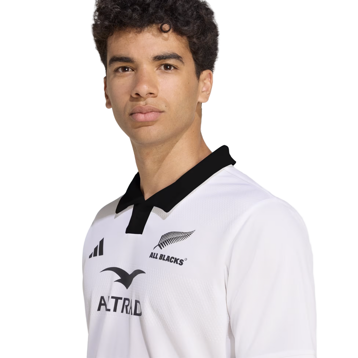 A person stands against a plain background wearing the adidas All Blacks 25/26 Replica Away Jersey, featuring a white design with a black collar.
