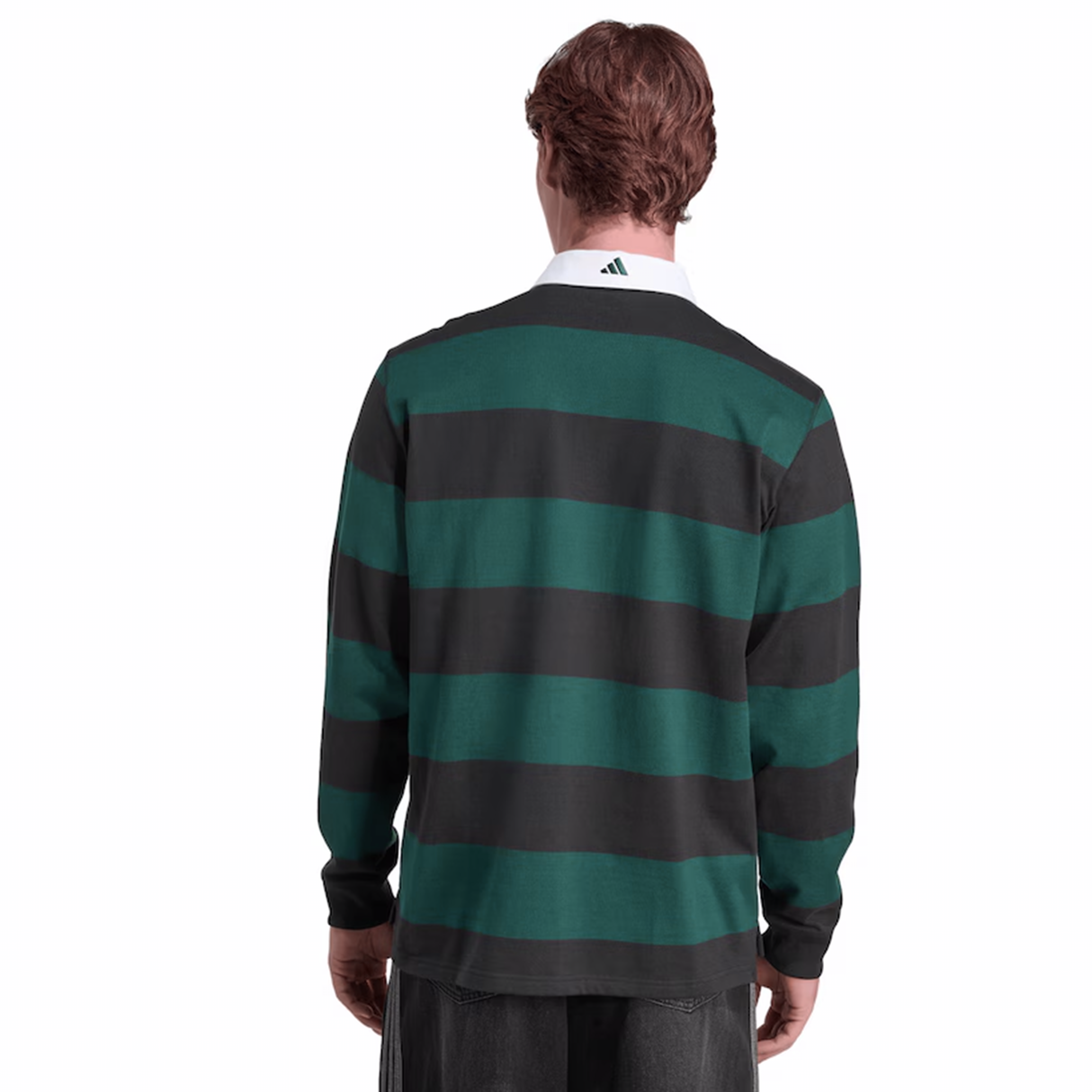 A person wearing the adidas All Blacks 25/26 Long Sleeve Heritage Polo, featuring green and black stripes and a white collar, stands facing away from the camera.