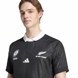 A person wearing the Black Ferns WRWC25 Replica Home Jersey by adidas, a black patterned rugby top inspired by WRWC25, featuring Black Ferns and Rugby World Cup New Zealand 2021 logos.