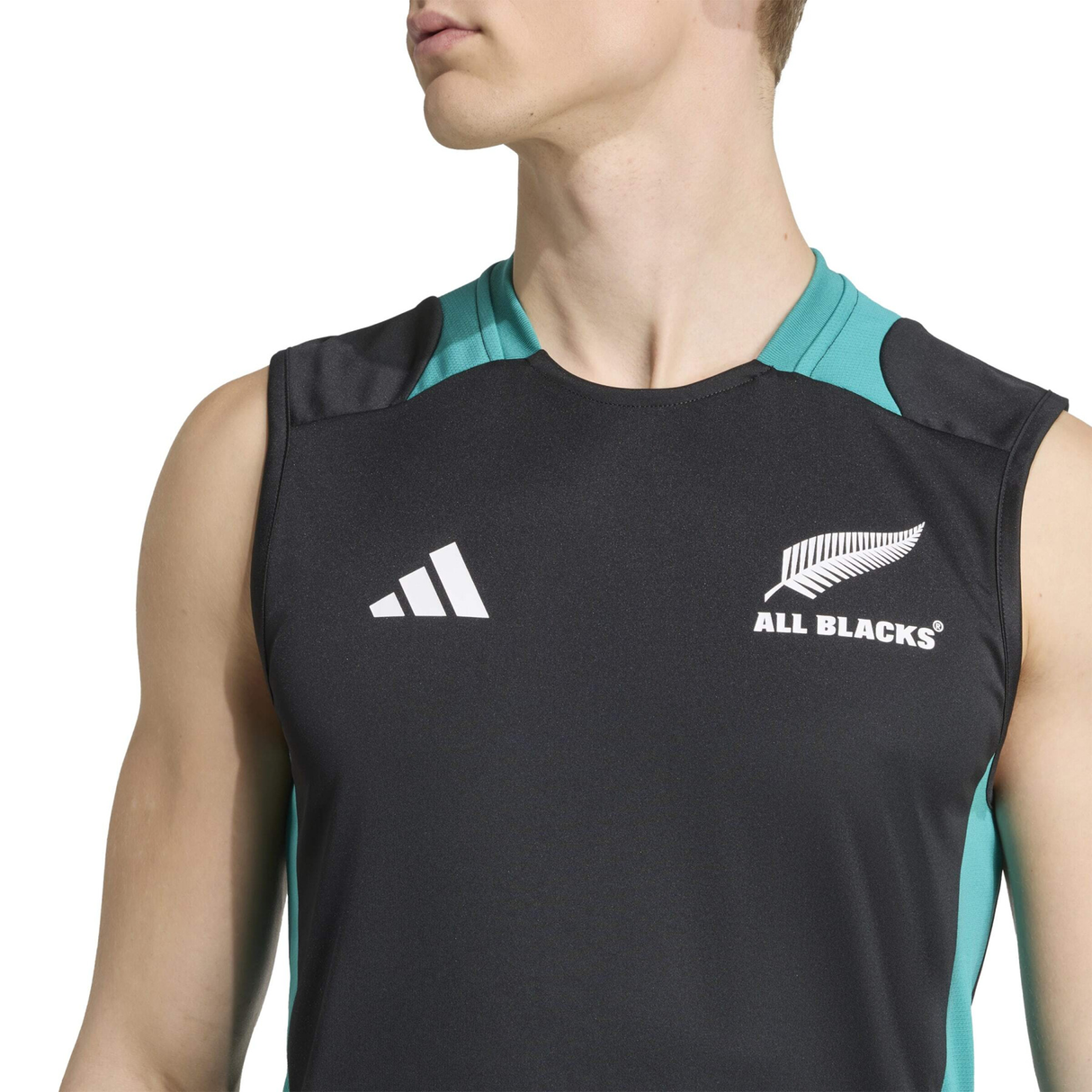 Someone in the All Blacks 25/26 Training Singlet by adidas—a black sleeveless sports jersey with team logos on the chest—looks to the side, gearing up for their next rugby training session.