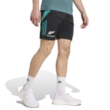 Sporting the adidas All Blacks 25/26 Training Gym Short in black with teal accents, a matching teal shirt, white adidas socks, and sneakers, this person highlights New Zealand rugby style against a white backdrop.